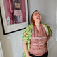A Dusty Rose T-Shirt, with cursive writing on it in white. In lowercase letters the first line reads “it’s”, the second line “videogames” spelt as one word, the third line “not” and the fourth line “video games” using two words. In the centre below the text is the Mighty Yell logo in black which features the illustration of a mountain and a person on top yelling. There are three small lines coming out of the person’s mouth.